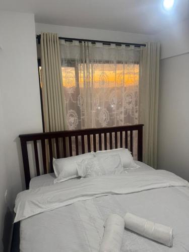 a bedroom with a white bed with a window at BonBon Residency in Kiambu