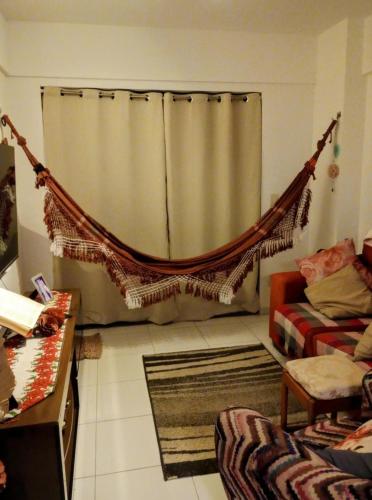 a living room with a hammock in front of a curtain at Alugo Quarto somente uma pessoa in Maceió