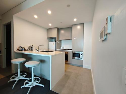 a kitchen with a counter and two stools in it at Modern Comfort Stay - Near Stadiums Green Spaces-19 in Sydney