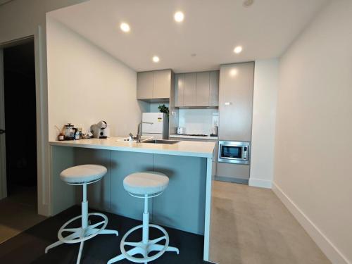a kitchen with two stools at a blue counter at Modern Comfort Stay - Near Stadiums Green Spaces-19 in Sydney