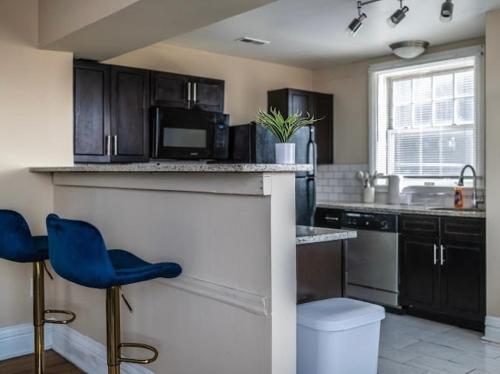 a kitchen with a counter and two blue chairs at The Cozy Luxe Retreat, Central West End in Saint Louis