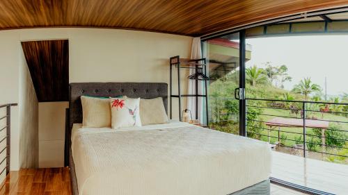 a bedroom with a bed and a large window at Cabañas Caeli, El Colibri, NEW La Fortuna Rainforest Cabin w Panoramic Views in San Francisco