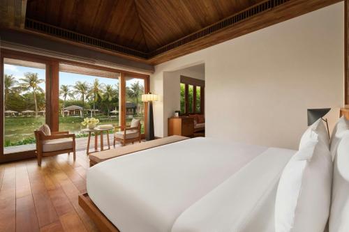Un dormitorio con una gran cama blanca y una sala de estar. en Legacy Mekong, Can Tho, Autograph Collection, en Can Tho