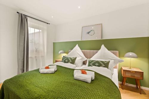 a bedroom with a green and white bed with towels on it at Superior Apartment Dingolfing - Design & Komfort in Dingolfing