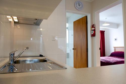 a kitchen with a sink and a room with a couch at Bucket Tree Lodge in Tawa