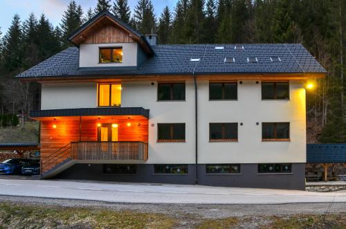 een wit huis met een zwart dak bij Apartmaji nad potokom in Železniki