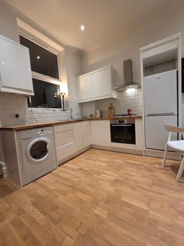 a kitchen with white cabinets and a washer and dryer at Camden Mia Apa in London