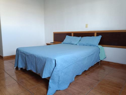 a bed in a room with a blue blanket on it at Gutemberg Palace Hotel in Nova Serrana