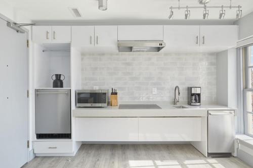 a white kitchen with a sink and a microwave at The King Street House By Kasa in Alexandria