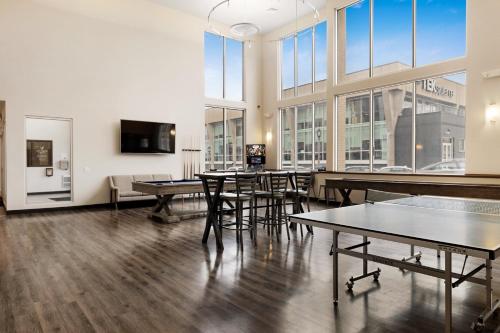 Kasa Westown Milwaukee في ميلووكي: غرفة كبيرة بها طاولات وكراسي ونوافذ