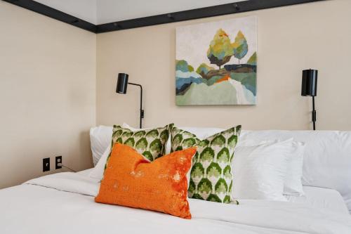 a white bed with two orange pillows on it at The Maverick By Kasa in Pittsburgh