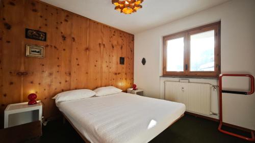 una camera con un letto bianco e una parete in legno di La Betulla a Verrand