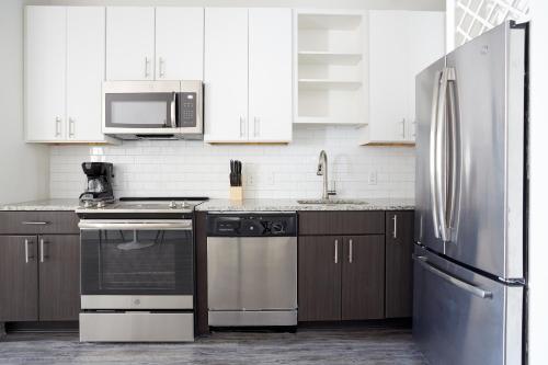 a kitchen with white cabinets and a stainless steel refrigerator at Kasa Altmayer Savannah in Savannah