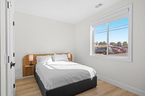 a white bedroom with a bed and a window at The Loop Downtown By Kasa in Traverse City