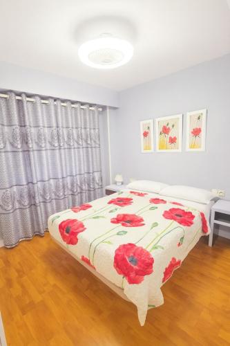 a bedroom with a bed with a red flower blanket at Luxury A Huertas 143 in Tomelloso