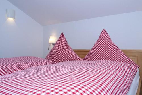 een rood-wit geblokt bed met rode kussens bij Ferienhaus Alpenflair bei Schliersee in Schliersee