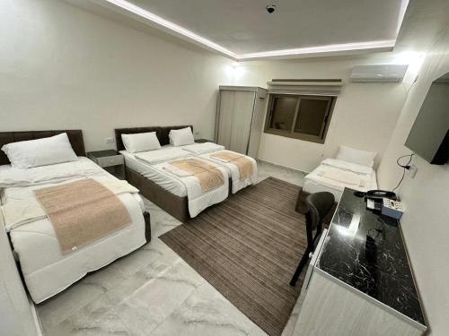 Una habitación de hotel con dos camas y un escritorio. en Mountain Echo Inn, en Taiyiba