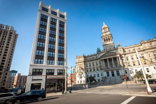 a car driving past a building with a clock tower at Kasa Cadillac Square Detroit in Detroit