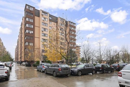 a parking lot with cars parked in front of a building at Apartament Militari Residence in Dudu