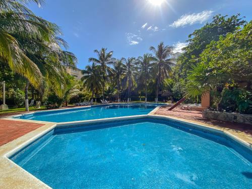 a swimming pool with palm trees in the background at Villas Tropical By Andiani in Cancún