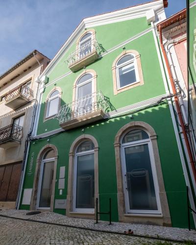 a green building with white windows on a street at Pharmácia- Alojamento local in Miranda do Corvo