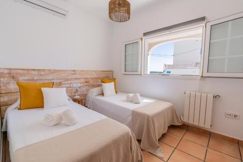 Casa Lucia a 500 m de la playa - Formentera Natural في لا سافينا: سريرين في غرفة ذات نافذتين