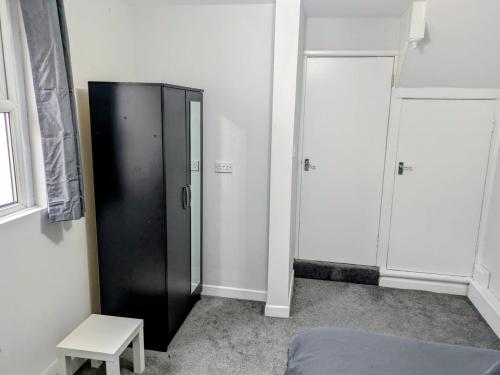 a black refrigerator in a room with a stool at Modern One Bedroom Flat With Garden in Cardiff