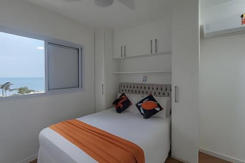 una camera da letto bianca con un letto e una finestra di Brisa do Mar - Varanda/2 qtos/Est/Ar a Campo Grande