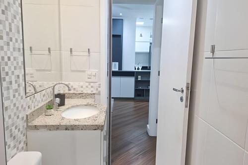 un bagno con lavandino e specchio di Brisa do Mar - Varanda/2 qtos/Est/Ar a Campo Grande