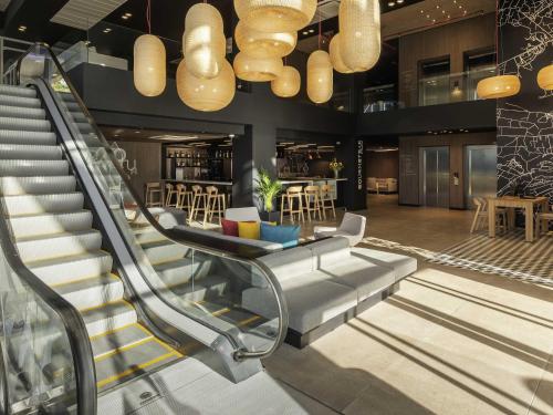 a lobby with a staircase with a couch and chairs at Novotel Santiago Providencia in Santiago