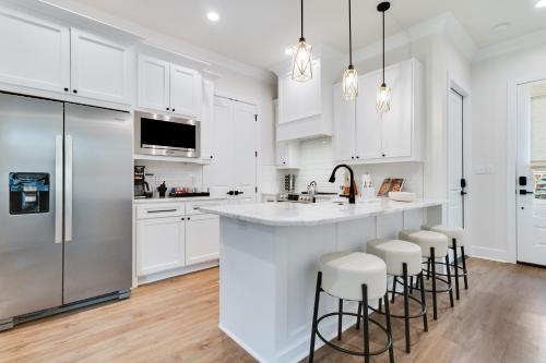 a kitchen with white cabinets and a large island with bar stools at Brand New Designer Townhome in the Middle of Town in Lafayette