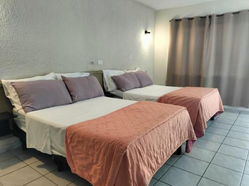 two beds sitting next to each other in a room at Hotel Virrey in Reynosa