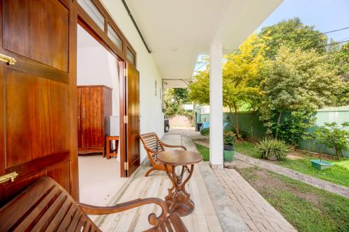 Un porche con dos bancos y una mesa. en Villa Tanzanite Hikkaduwa, en Hikkaduwa