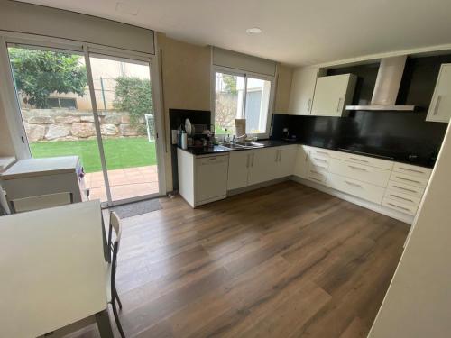 a large kitchen with white cabinets and a wooden floor at Stunning Villa 25' from Barcelona in Las Canteras