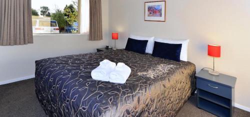a bedroom with a bed with two white shoes on it at Anika Motel in Christchurch