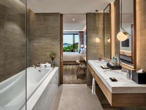 a bathroom with a tub and a sink and a bed at Premier Residences Phu Quoc Emerald Bay Managed by Accor in Phu Quoc