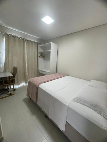 une chambre avec un grand lit blanc et un bureau dans l'établissement Morada Pinheiro 160m da Praia, à Bombinhas