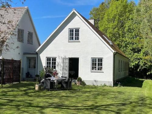 una casa blanca con una mesa en el patio en Æblehuset Ved Historisk Gods På Sydsjælland, en Præstø