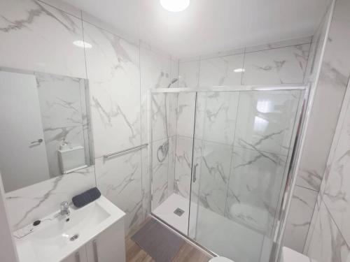 a white bathroom with a shower and a sink at Spacious 3BR Condo With Pool, Wifi & Near Beach in Callao Salvaje