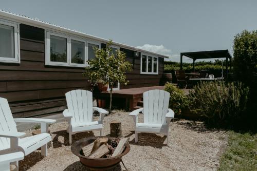 three white chairs and a table in front of a house at The Pickers Rest in Tasman