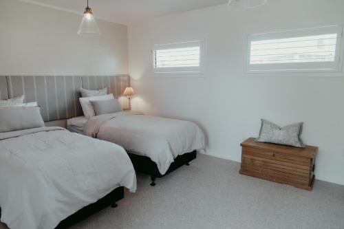a bedroom with two beds and a table and two windows at The Pickers Rest in Tasman