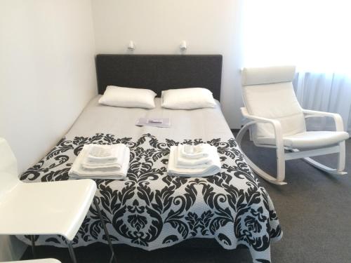 a bedroom with a black and white bed and a chair at Valentine's White Lux in Kuldīga
