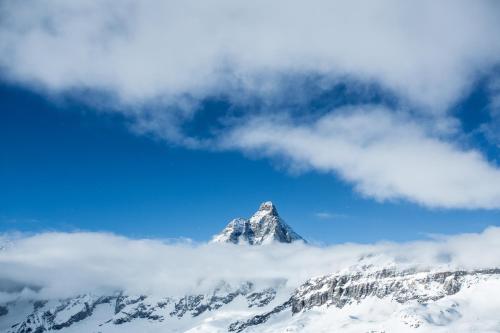 a mountain covered in snow and clouds in the sky at Ski Gate - Main Street by Cervino View Experience in Breuil-Cervinia