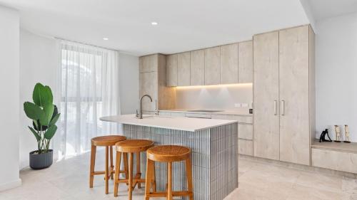 a kitchen with wooden stools and a kitchen island at Pacific Chill 2 Mins Walk to Beach in Hawks Nest