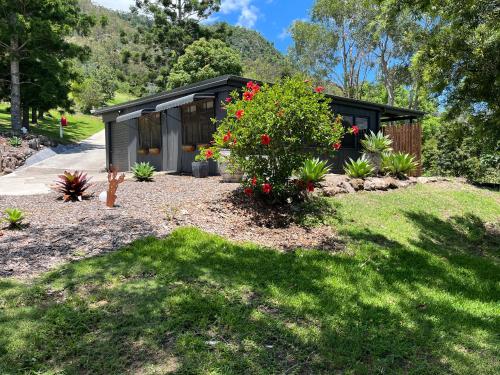 The Archer Retreat في Villeneuve: منزل صغير أسود اللون مزين بأزهار حمراء في فناء