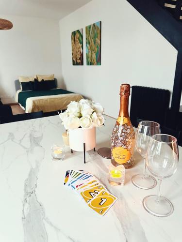 a table with a bottle of champagne and two wine glasses at Grand Studio WiFi rapide RER B in Sevran