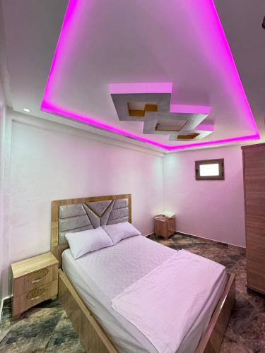 um quarto com uma cama com uma iluminação rosa em Best house in taghazout em Taghazout