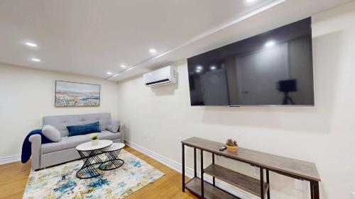 a living room with a couch and a tv on the wall at Cozy Basement Apartment for 4 - Near Cafes & Parks in Toronto