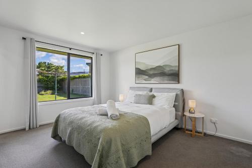 ein weißes Schlafzimmer mit einem Bett und einem Fenster in der Unterkunft Cosy 4 Bedroom Home in Queenstown Airport