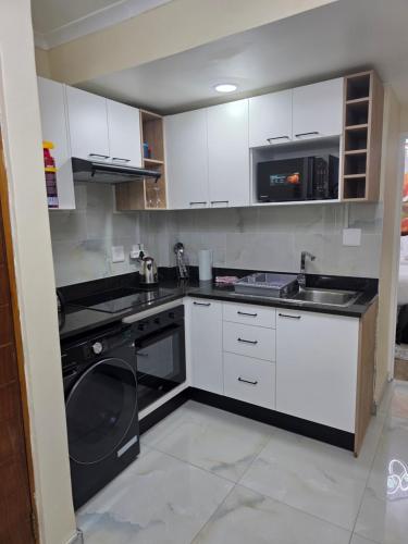 a kitchen with white cabinets and a washing machine at The Oceanic 42 in Durban